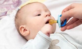 Little caucasian boy baby and dummy. Orthodontic pacifier for children. Formation of bite in children, close-up photo