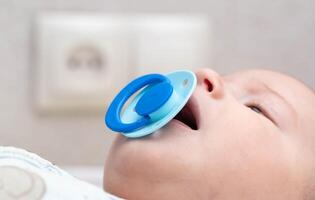 Blue latex pacifier in baby's mouth. The concept of orthodontic comfortable nipple without changing the bite in children, close-up. Copy space for text photo