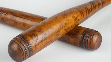 Two beautifully crafted wooden bats lie crossed on a white surface, highlighting their design photo