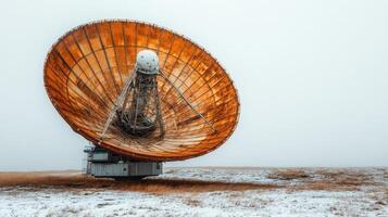 A huge rusty satellite dish towers over the snowy ground, embodying winter's essence photo