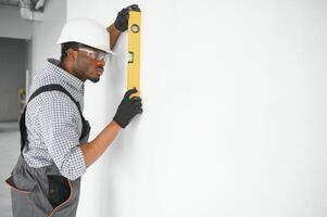 Construction worker observing and surveying wall alignment using water level photo