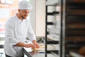 pastry chef making some croissant in the bakery photo