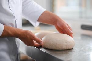 baker making bread , man hands , kneading a dough , cooking coat photo