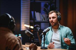 Show host and guest meeting to stream podcast episode together, creating online content with live broadcast discussion. Vlogger talking to man using professional equipment to record chat photo