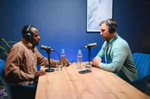 Show host and guest meeting to stream podcast episode together, creating online content with live broadcast discussion. Vlogger talking to man using professional equipment to record chat photo