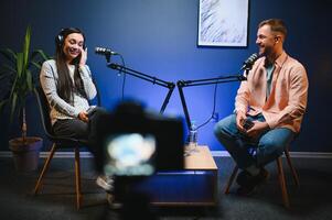 Side view of successful woman hosting podcast interviewing man while recording with professional microphones, copy space photo