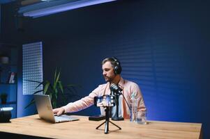 vlogger using smartphone to film podcast in studio. blogger with mobile phone, microphone and headphones filming for social media broadcasting career photo