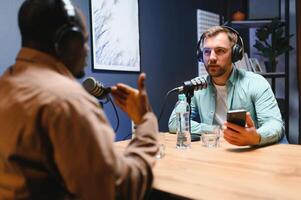 Show host and guest meeting to stream podcast episode together, creating online content with live broadcast discussion. Vlogger talking to man using professional equipment to record chat photo
