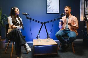 Side view of successful woman hosting podcast interviewing man while recording with professional microphones, copy space photo