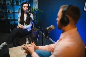 Two Young Stylish Radio Show Hosts Record Fresh Podcast Episode in Studio. Attractive Energetic Co-hosts Discuss Important Topics Live on Air in an Evening Show photo