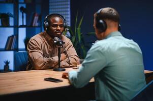 Show host and guest meeting to stream podcast episode together, creating online content with live broadcast discussion. Vlogger talking to man using professional equipment to record chat photo