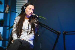Female podcaster in headphones interviewing man guest using microphone, smiling, recording and broadcasting audio podcast in studio. Content creator, blogging photo