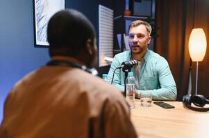 Man podcaster influencer blogger smiling while broadcasting his live audio podcast in studio using headphones. Male radio host making podcast or interview photo