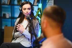 Side view of successful woman hosting podcast interviewing man while recording with professional microphones, copy space photo