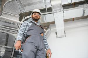 An Indian worker inspects the ventilation system in an office building photo