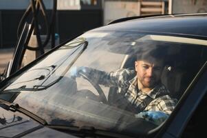 Feeling happy to be doing an excellent job at my job at the car wash. Portrait of a man while sitting inside a customer vehicle photo