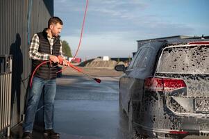 Car is washed at a professional car wash. Man washes a car with foam. Detailing photo