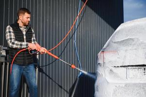 Car is washed at a professional car wash. Man washes a car with foam. Detailing photo