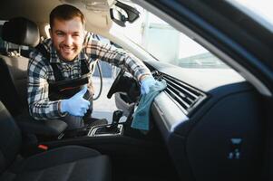 Feeling happy to be doing an excellent job at my job at the car wash. Portrait of a man while sitting inside a customer vehicle photo