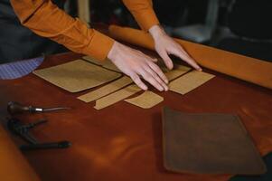 Tailor cobbler hold different rolls natural brown leather, working with textile in workshop photo