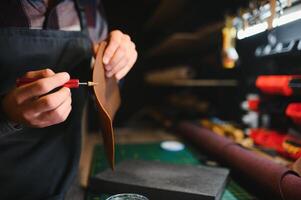 Man working with leather. Professional makes a wallet. photo