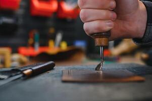 Man working with leather. Professional makes a wallet. photo