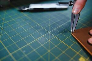 Man working with leather. Professional makes a wallet. photo