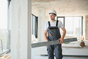 Builder in working uniform cutting metal profile with cutting machine at the construction site indoors photo