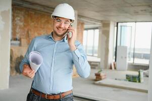 With plan in hands. Man in uniform is working on the construction site photo