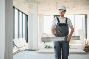 Builder in working uniform cutting metal profile with cutting machine at the construction site indoors photo