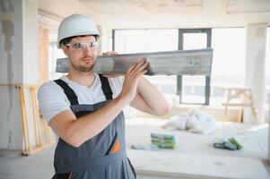 Builder in working uniform cutting metal profile with cutting machine at the construction site indoors photo