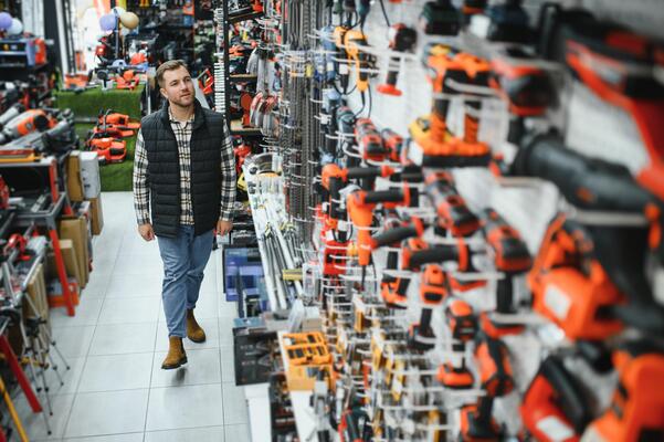 A man chooses a power tool in a hardware store