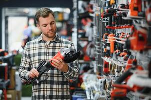 A man chooses a power tool in a hardware store photo
