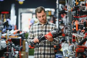 A man chooses a power tool in a hardware store photo