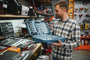 A male buyer chooses a toolbox in a hardware store. A large selection of tools. photo