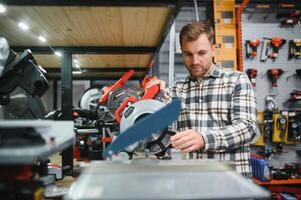 A male buyer chooses power tools in a hardware store. A large selection of tools photo