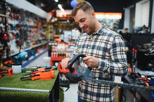 a man chooses a brushcutter in a hardware store photo