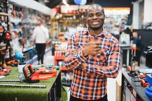 Confident smiling salesman on foreground in power tools store. Guy is ready to help clients on background photo