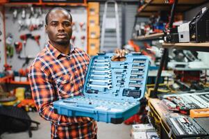African american male buyer chooses a toolbox in a hardware store. A large selection of tools photo
