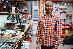 Confident smiling salesman on foreground in power tools store. Guy is ready to help clients on background photo