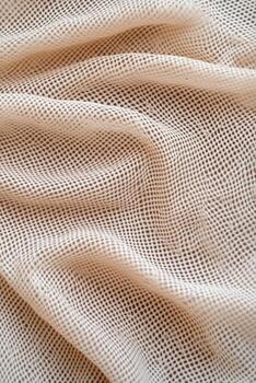 Soft beige mesh fabric draped elegantly on a surface photo