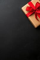 Beautifully wrapped gift with red ribbon on dark background photo