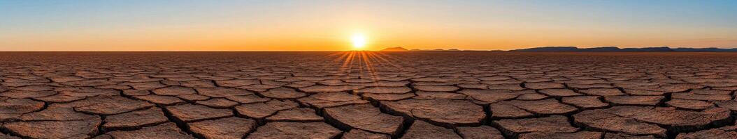 Sunset over a cracked desert landscape showcasing drought impact photo