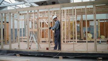 Handsome man builder working at prefabricated house building construction site video