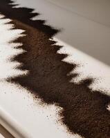 Abstract Textured Design of Dark Coffee Grounds on White Canvas with Natural Light photo