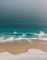 Aerial view of turquoise ocean waves crashing on sandy beach photo