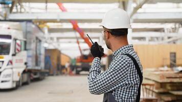 Foreman instructing worker in construction crane using walkie talkie radio. Engineer manages the loading of a prefabricated modular house to truck video
