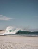 A beautiful beach with a large wave crashing on the shore photo