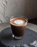 Glass of iced chocolate coffee with creamy froth served on dark textured background photo