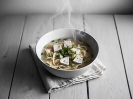 Chicken noodle soup in black bowl with garnish on wooden table. photo